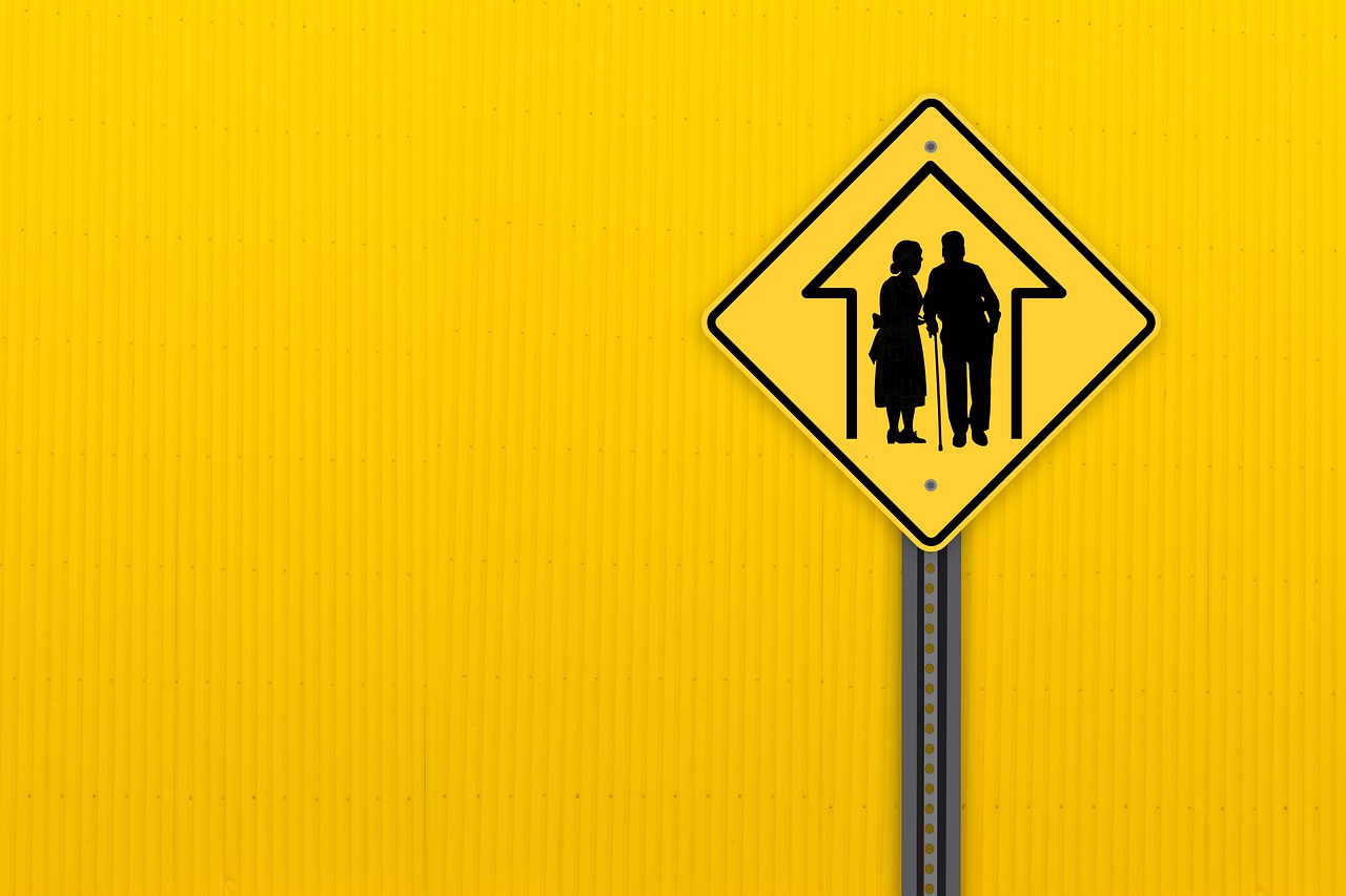 Road sign with pictogram for the nursing home, against yellow background.